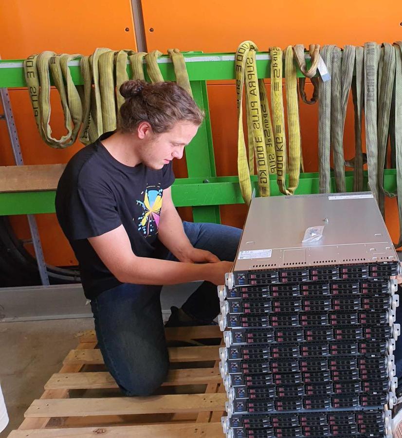 Chandler Baker '24 unpacks servers at CERN to create a large computing farm of about 50,000 processing applications that the software-based High Level Trigger uses to analyze new data from ATLAS Experiment at CERN. 